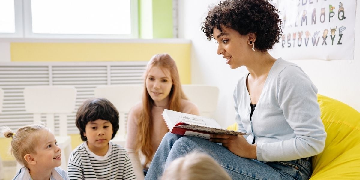 teacher reading to children sitting on the floor 
