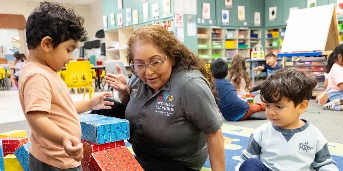 Options for Learning teacher playing with toy bricks with two toddler-aged boys