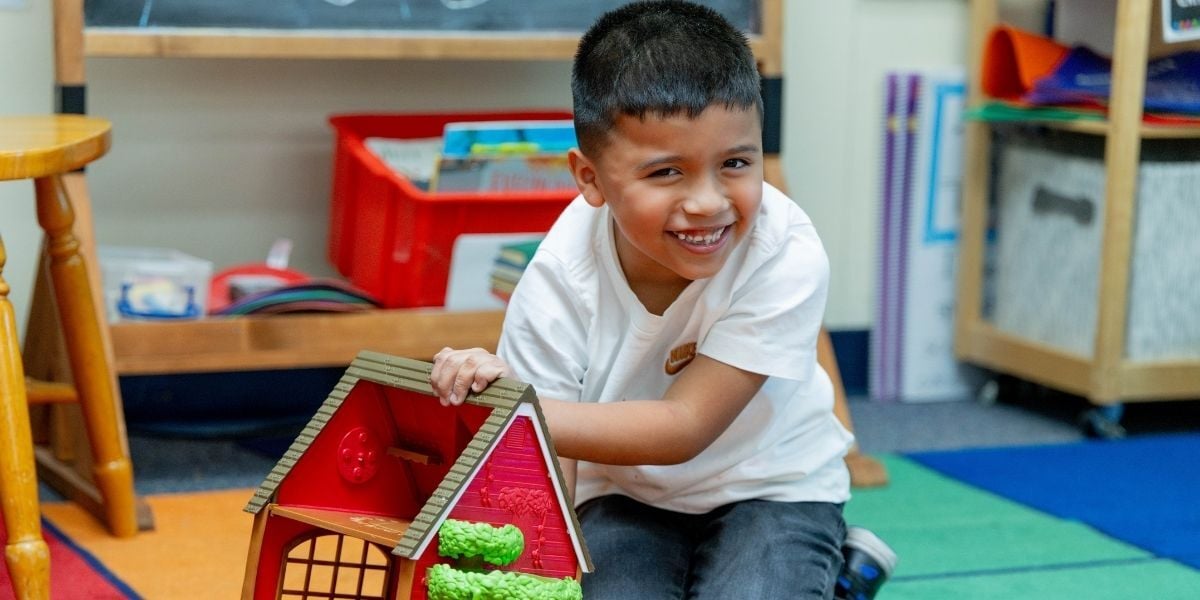 boy laughing while playing with a toy house