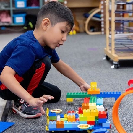 young boy playing with legos in a classroom
