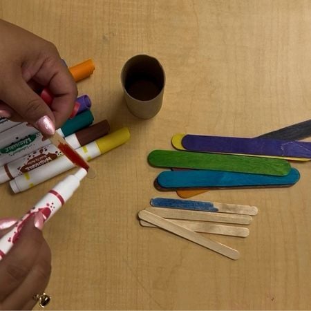 teacher coloring in a popsicle stick with a red marker