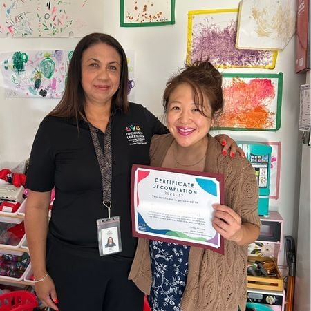 Cindy Alvarez, a parent coach from Options for Learning, stands next to a parent holding a certificate of completion