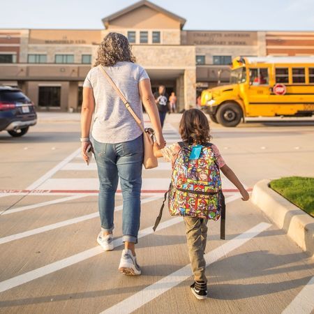 a mom dropping off their son at preschool who is wearing a Super Mario Bros. backpack and jeans