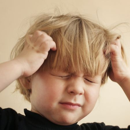 a young boy itches his blond hair and closes his eyes