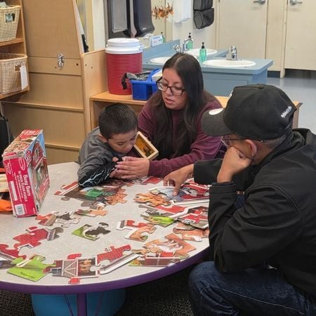 an Options for Learning parent coach helps a parent and a child with a puzzle at a table
