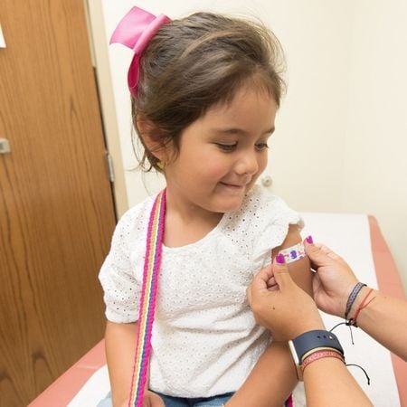 girl getting a band aid put on her arm