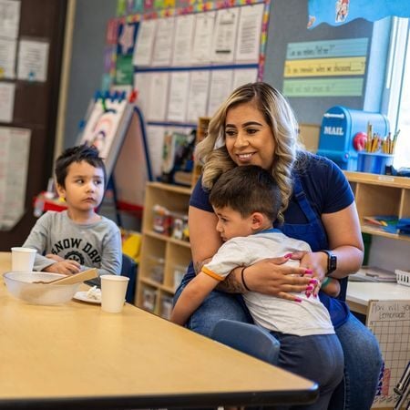 teacher hugging a toddler aged boy