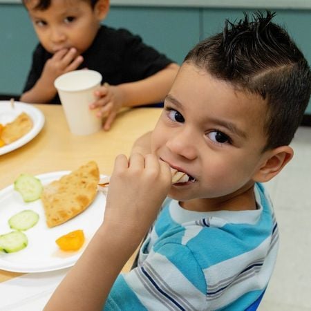 little boy eating a piece of pita