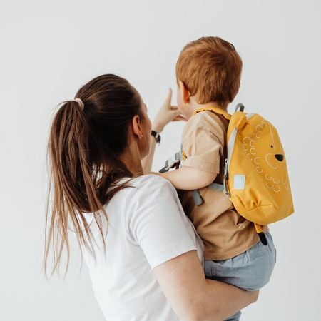 mom carrying boy with a backpack