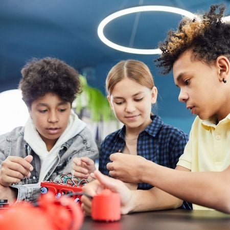 three pre-teen children (two boys and a girl) build a robot together