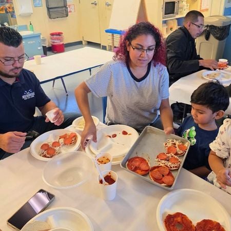 a mom holds a plate of homemade pizza and puts it on her son's plate