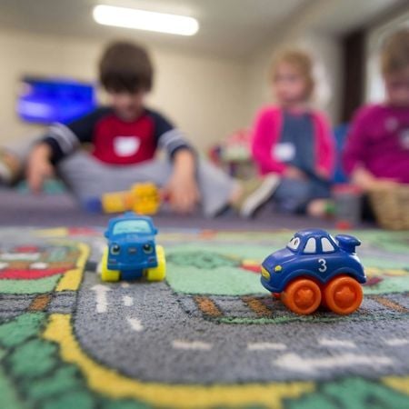2 toy cars on a carpet in a children's classroom