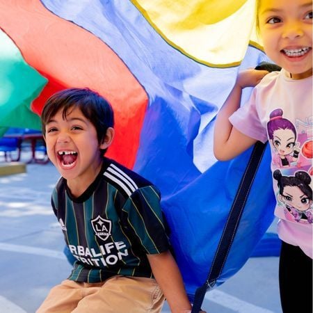 a young boy and girl under a parachute and smiling