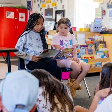 Two girls in an Options for Learning classroom read outloud in front of their classmates
