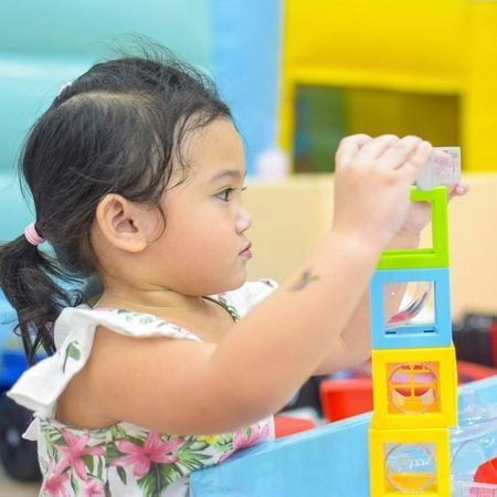 a young girl playing with colorful square blocks