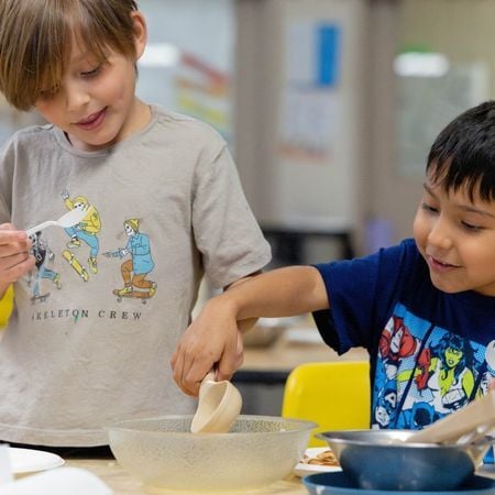 two children in a classroom smiling