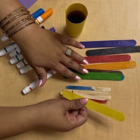a teacher holding a colored popsicle stick