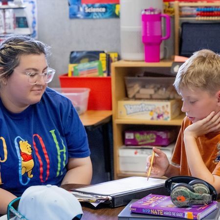 an Options for Learning teachers helps a young boy complete a worksheet