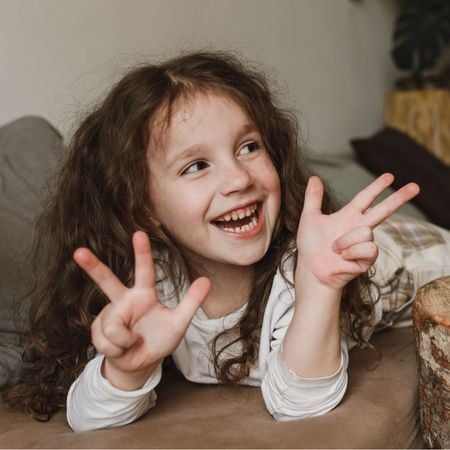 girl holding up 6 fingers and smiling