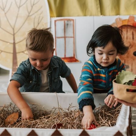 two boys playing in a garden sensory bin