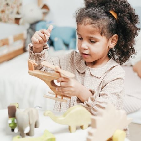 preschool age girl holding a wooden plane