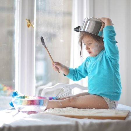 child using a pot as a musical instrument on the kitchen counter