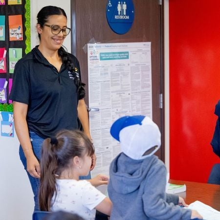 Options for Learning teacher smiling at two toddler-aged children