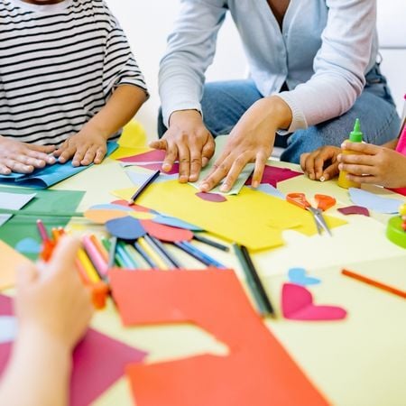a group of students and a teacher doing arts and crafts with paper pencils and colorful paper