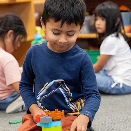 a young boy in a classroom playing with Legos