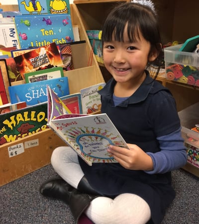 Preschool girl reading a Dr. Seuss book in class