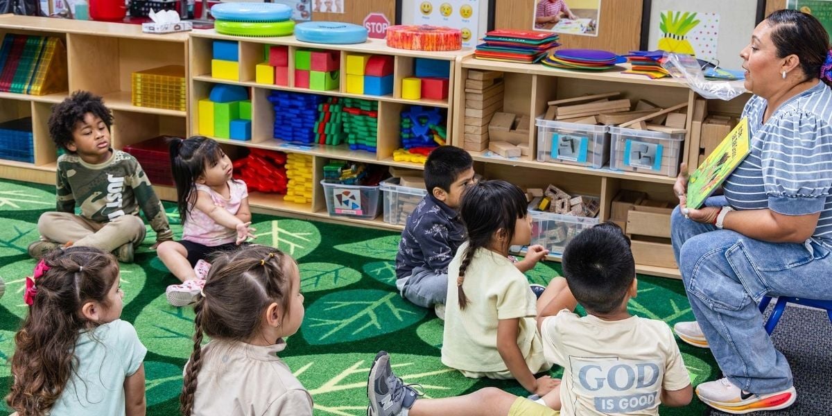 preschool children sitting on a carpet while a teacher is reading to them