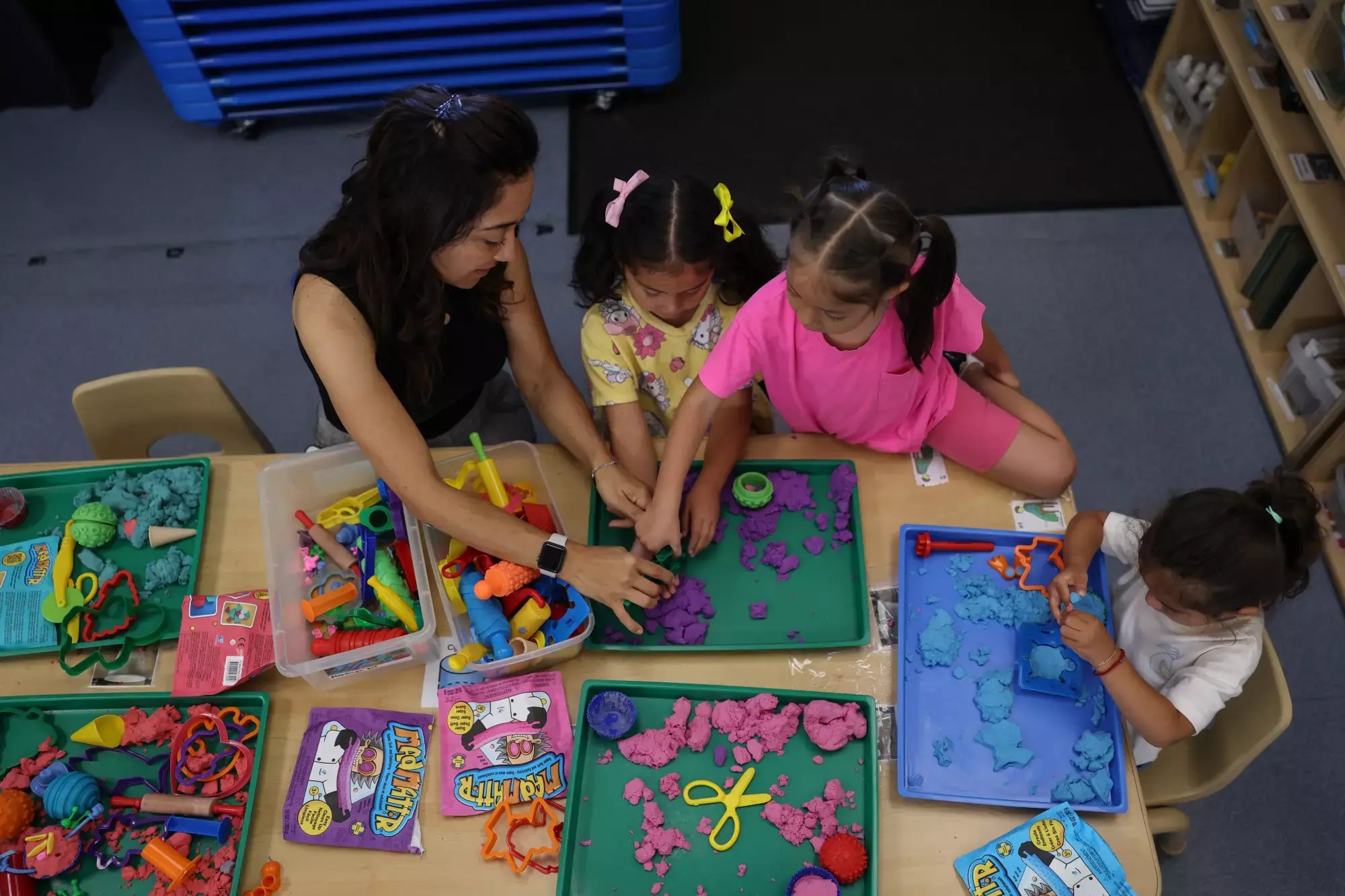 A teacher and preschool children working on a project at a table